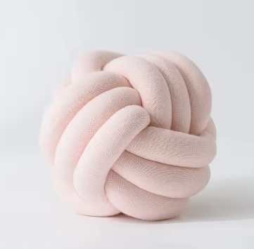 Chunky gevlochten knoopkussen in lichtroze kleur – een delicate en speelse touch voor je interieur.
