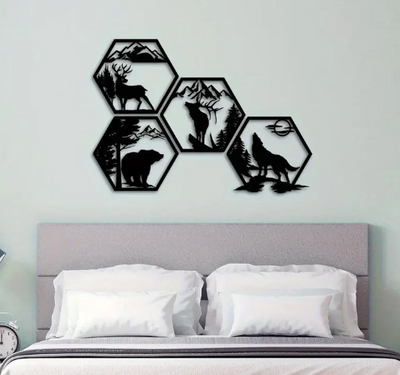 Zwarte metalen wanddecoratie boven bed – 5 zeshoekige panelen met silhouetten van hert, beer, wolf en berglandschap – natuurkunst op lichtgekleurde muur in moderne slaapkamer met grijs hoofdbord en witte lakens.