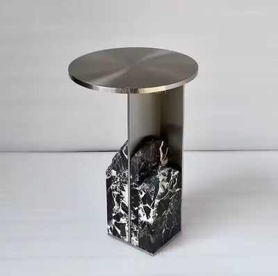Design bijzettafel met rond metallic tafelblad en verticale metalen poot, ondersteund door zwart-wit marmeren structuur in organische vorm, eigentijds accentstuk voor modern interieur