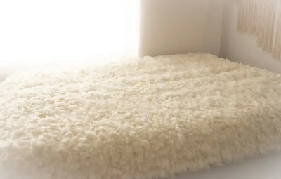Rand van het schapenvacht vloerkleed met zichtbare afwerking, op houten vloer, benadrukt de dikte en kwaliteit van het materiaal