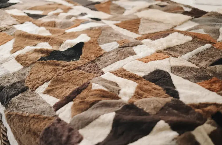Close-up van een gebreide deken in grafisch patroon met scherpe lijnen en neutrale kleurvlakken