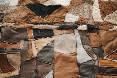 Detail van een deken met geometrisch patroon in bruin, zwart en wit garen, zichtbaar weefsel en natuurlijke textuur