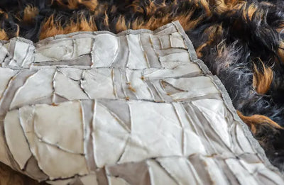 Onderzijde van een wandtapijt met zichtbare stiknaden, lichte backing en randafwerking; gecombineerd met detail van een donkere harige dierenhuid ernaast