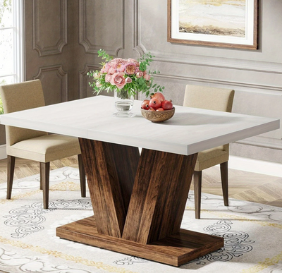 Eettafel met wit rechthoekig tafelblad en V-vormig houten onderstel, geplaatst in een klassiek ingerichte eetkamer met bloemen en fruit op tafel.