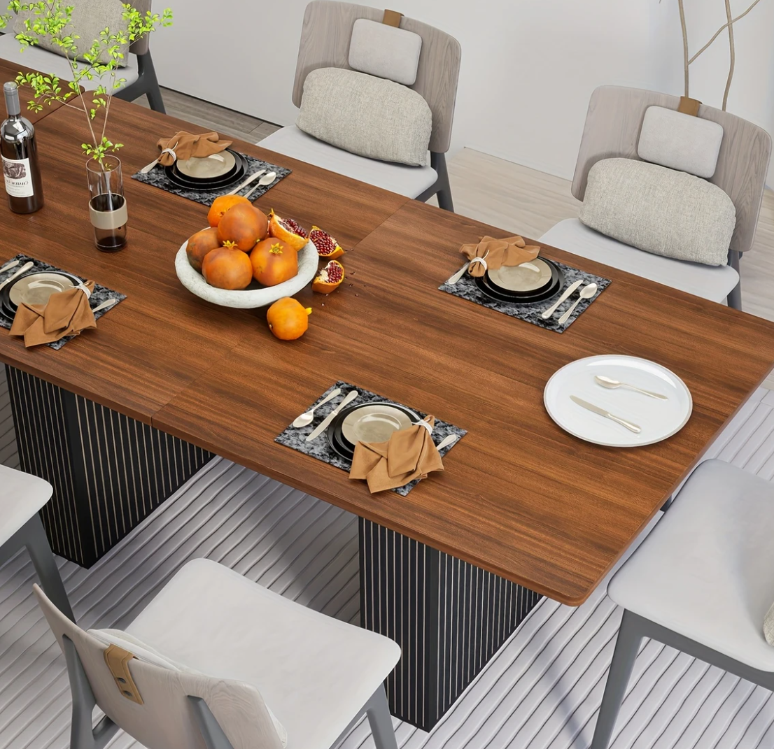 Gedekte tafel in gebruik, met fruit en servies, omringd door acht stoelen in een eetkamer.
