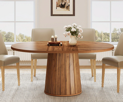 Ovale houten eettafel van 140 cm met cilindrische poot, omringd door vier beige stoelen in een lichte eetkamer.