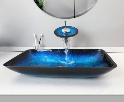 Blauw glazen waskom met ronde watervalkraan en chroom details – moderne badkameropstelling.