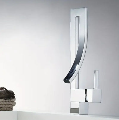 Design wastafelkraan in glanzend chroom met gebogen uitloop en eengreeps bediening, gemonteerd op witte wastafel met stapel opgerolde handdoeken ernaast; elegant accent in een moderne badkamer met neutrale achtergrond