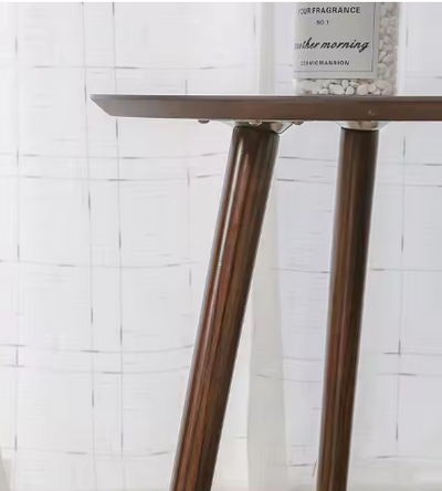 Close-up van een houten bijzettafel met schuine poten en glad tafelblad, gedecoreerd met een cilindervormige geurcontainer. Achtergrond met witte gordijnen en subtiel rasterpatroon — een minimalistische en stijlvolle interieursetting met natuurlijke texturen.