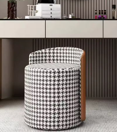 Design kruk met houndstooth-stof en leren zijpaneel voor witte bureau in modern interieur met verticale wandpanelen en decoratieve accessoires.