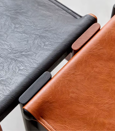 Detail van Japanse retro eetkamerstoelen met zwart en bruin olie wax leren zitting, bevestigd met houten cilindervormige pennen — ambachtelijk vakmanschap en hoogwaardige materialen in minimalistisch design geïnspireerd op de traditionele monnikstoel.