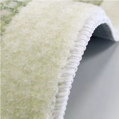 Detailafbeelding van de omgeplooide rand van een lichtgekleurd fluffy vloerkleed, toont beige of crèmekleurige hoogpolige textuur aan bovenkant en wit gestikte afwerking langs de rand; onderzijde heeft een glad en stevig oppervlak dat de antislipfunctie ondersteunt, een kwaliteitsvol detailbeeld dat de duurzaamheid en afwerking van het vloerkleed benadrukt