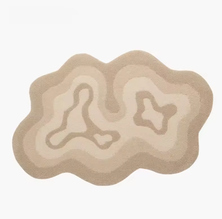 Fluffy vloerkleed in organische vorm met concentrisch patroon in beige en crème tinten; design doet denken aan topografische lijnen met centrale vormen die lijken op abstracte eilandjes; afgebeeld in neutrale setting zonder meubilair, een hoogpolig en zacht vloerkleed dat rust en stijl toevoegt aan een modern interieur