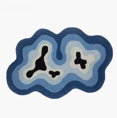 Fluffy vloerkleed in organische vorm met topografisch design in donkere en lichte blauwtinten, wit en zwarte accenten; golvend patroon doet denken aan waterlijnen of eilanden, afgebeeld zonder meubels op neutrale ondergrond; een modern en hoogpolig tapijt dat rust en visuele diepte toevoegt aan elk interieur