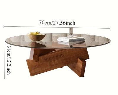 Moderne ronde salontafel met transparant gehard glasblad en houten onderstel, diameter 70 cm en hoogte 31 cm; tafel gedecoreerd met houten schaal met inhoud en stapel magazines, geplaatst in eigentijdse setting, een stijlvol en luchtig accent voor compact interieur