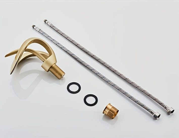 Onderdelen van een design wastafelkraan, uitgestald op witte ondergrond; zichtbaar zijn een goudkleurige gebogen uitloop met cilindrische basis, twee metalen aansluitbuizen met textuur, twee zwarte O-ringen en een kleine gouden koppelstuk; de set toont de technische elementen van een moderne kraan met sculpturale vormgeving en hoogwaardige afwerking