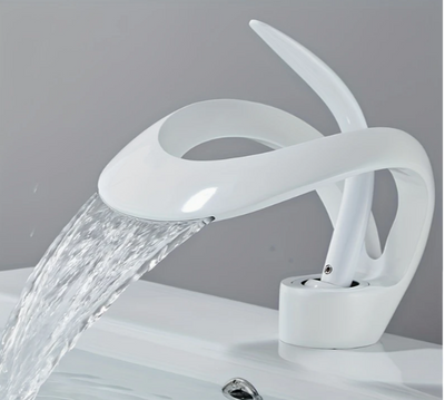 Design wastafelkraan in glanzende witte afwerking met sculpturale, lintvormige uitloop waaruit water vloeiend stroomt; kraan gemonteerd op witte wastafel met grijze achterwand, de artistieke vorm doet denken aan een sierlijke zwaan of gebogen lint, een elegante en moderne blikvanger voor hedendaags badkamerdesign