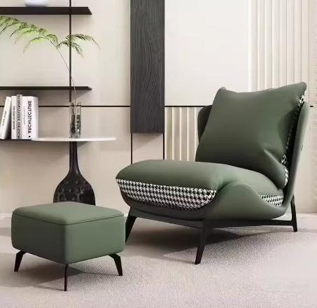 Loungefauteuil met bijpassende ottoman, uitgevoerd in groen kunstleer met pied-de-pouleprint op de zijkanten en achterzijde; de fauteuil is royaal bekleed en geplaatst in een modern interieur met beige wandpanelen, wandplanken met boeken en decoratieve accessoires zoals een zwarte bijzettafel met glazen vaas en plant; het geheel straalt comfort, elegantie en hedendaagse stijl uit—perfect voor woonkamer, loungehoek of leesruimte
