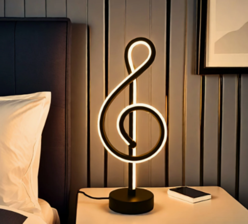 Decoratieve LED-lamp in de vorm van een solsleutel met warme witte lichtlijn op zwarte voet, op een houten nachtkastje naast een smartphone; achtergrond van verticale houten panelen, wit kussen en donkergrijs hoofdeinde.