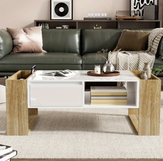 Moderne rechthoekige koffietafel van 105 cm met wit tafelblad en houtkleurige frame met lade en open vakken; lade deels geopend en bovenzijde gedecoreerd met houten tray met glazen pot en decoratieve objecten; geplaatst voor groene leren sofa met kussens en plaid, achtergrond toont wandkast met boeken, platenspeler en woonaccessoires; een sfeervol en functioneel middelpunt in eigentijdse woonkamer