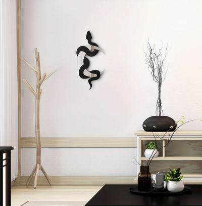 Wanddecoratie in moderne interieurhoek met abstracte zwarte slang- en maanvormige acrylkunst op licht muurvlak met houten rand; links een houten kapstok met organische vorm, rechts een houten wandplank met zwarte vaas met droogtakken en groene plant; op de voorgrond een zwarte tafel met glazen vaas en wit potje met groen blad; het verticale design (40 x 20 cm) combineert mystieke symboliek en minimalistische flair, perfect voor spiritueel geïnspireerde of moderne woonstijlen